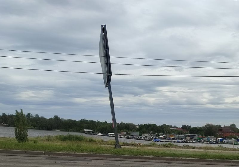 Опасно накренившийся рекламный щит мог не выдержать порывов штормового ветра